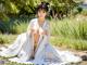 A woman in a white kimono sitting on the ground.