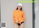a woman wearing an orange shirt and black shorts