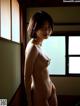 A nude woman standing in front of a window.
