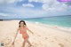 A woman in a pink bikini running on a beach.