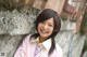 A young woman leaning against a stone wall.