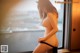 A woman in a black lingerie standing by a window.