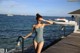 A woman in a bathing suit standing on a dock by the water.