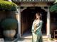 A woman in a green kimono standing in front of a building.