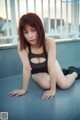 A woman in a black bathing suit sitting on a ledge.